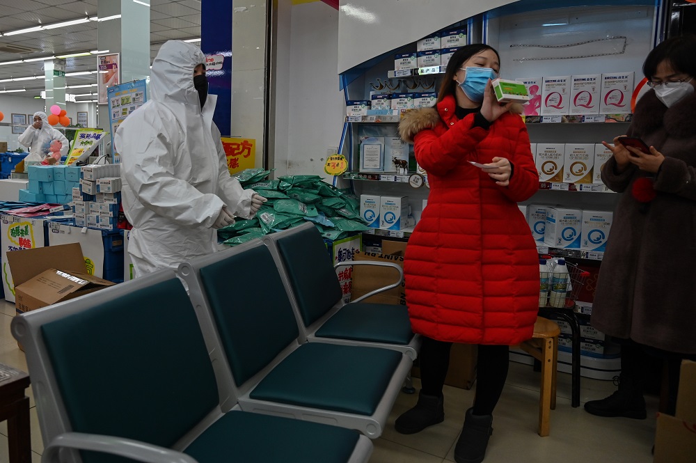 Pharmacy workers wearing protective clothes and masks serve customers in Wuhan January 25, 2020. u00e2u20acu201d AFP pic