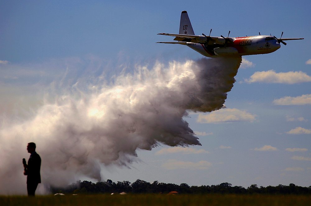 A television reporter stands in front of a Large Air Tanker (LAT) C-130 Hercules as it drops a load of around 15,000 litres during a display at RAAF Base Richmond Sydney, Australia September 1, 2017. u00e2u20acu201d Reuters pic