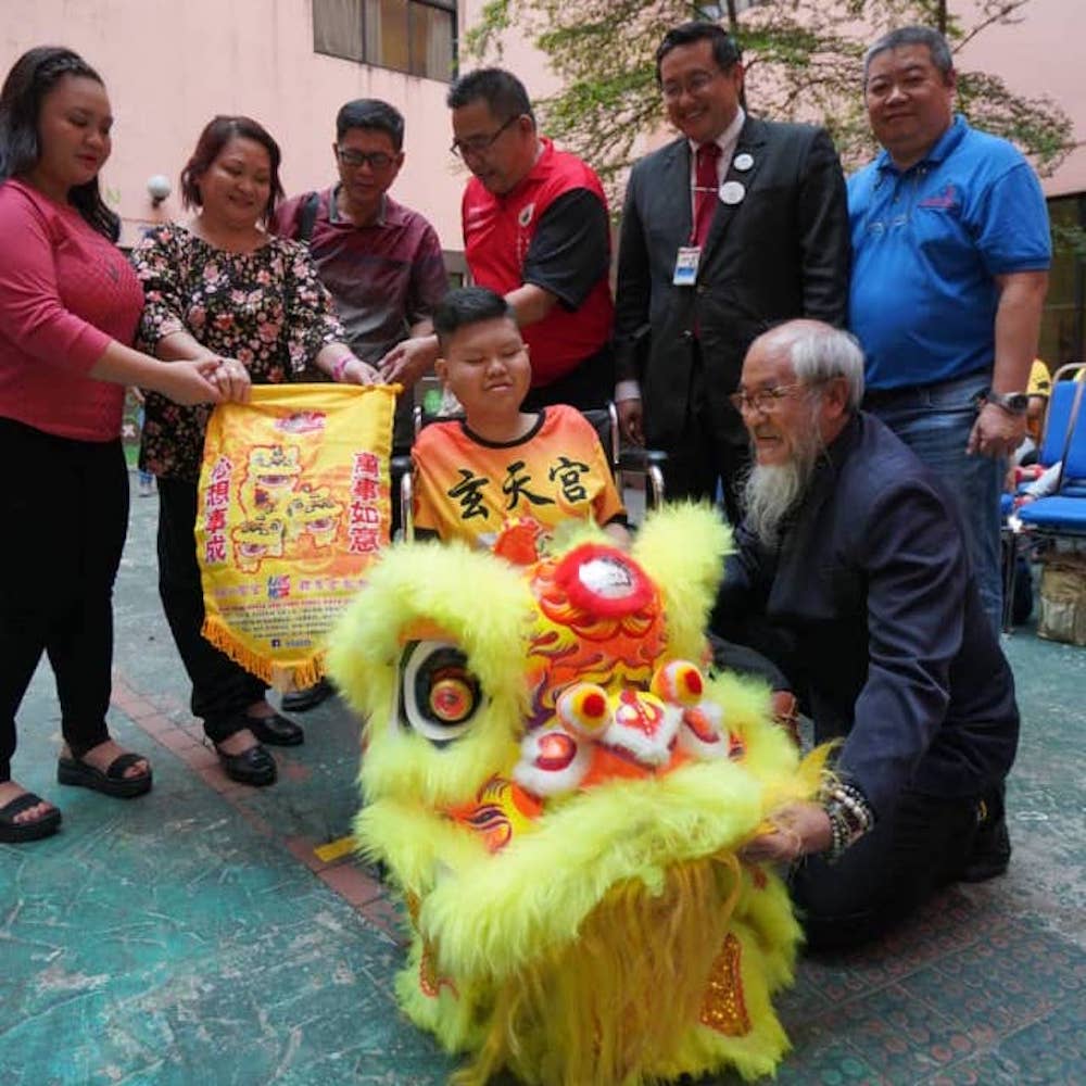 Annen (in orange) was over the moon when he got to meet Siow (bottom right), who has been crafting lion heads for more than 30 years. u00e2u20acu201d Picture courtesy of Teoh Teik Hoong