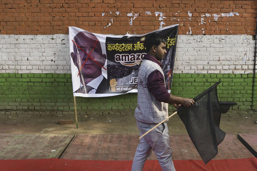 A trader hold a black flag as he walks next to a banner with the picture of Amazon CEO Jeff Bezos during a demonstration demanding the closure of online shopping platforms Amazon and Flipkart, in New Delhi, January 15, 2020. u00e2u20acu201d AFP pic