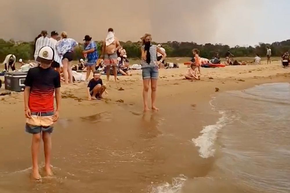 A crowd of people at the beach evacuate from the bushfires at Batemans Bay, Australia December 31, 2019. u00e2u20acu201d Image via INSTAGRAM@LAPPINGTHEISLAND via Reuters