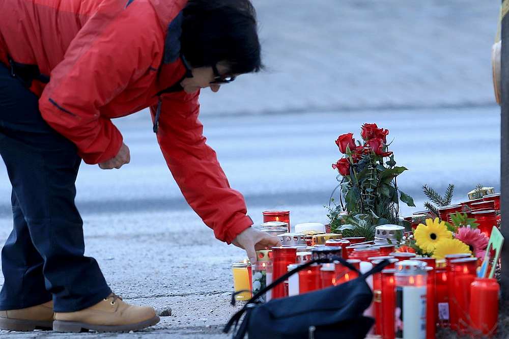 A woman puts a candle at a makeshift memorial on Via Aurina in Lutago (Luttach), South Tyrol, January 6, 2020. u00e2u20acu201d AFP pic