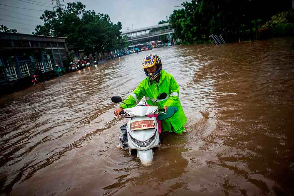 A man walks with his scooter through flood water after heavy rain in Jakarta, Indonesia January 1, 2020. u00e2u20acu201d Antara Foto/Aprillio Akbar pic via Reuters