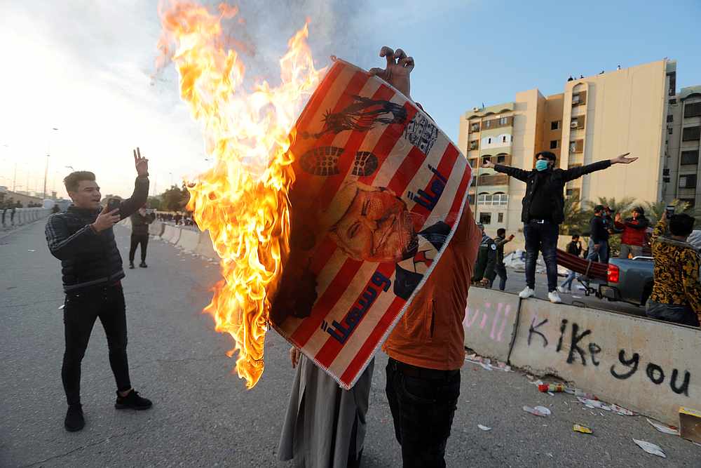 A protester holds a placard with US President Donald Trump illustration burning outside the US Embassy during a protest in Baghdad, Iraq January 1, 2020. u00e2u20acu201d Reuters pic 