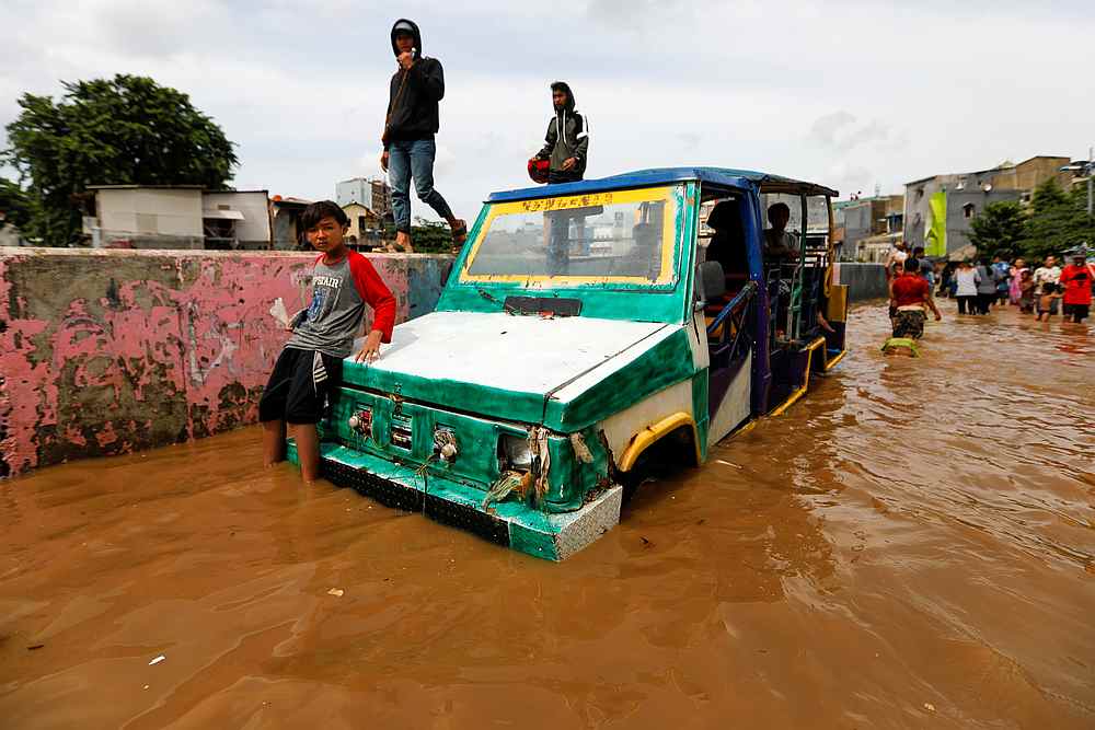 A young Indonesian sits on a car at an area flooded after heavy rains in Jakarta January 2, 2020. u00e2u20acu201d Reuters pic 