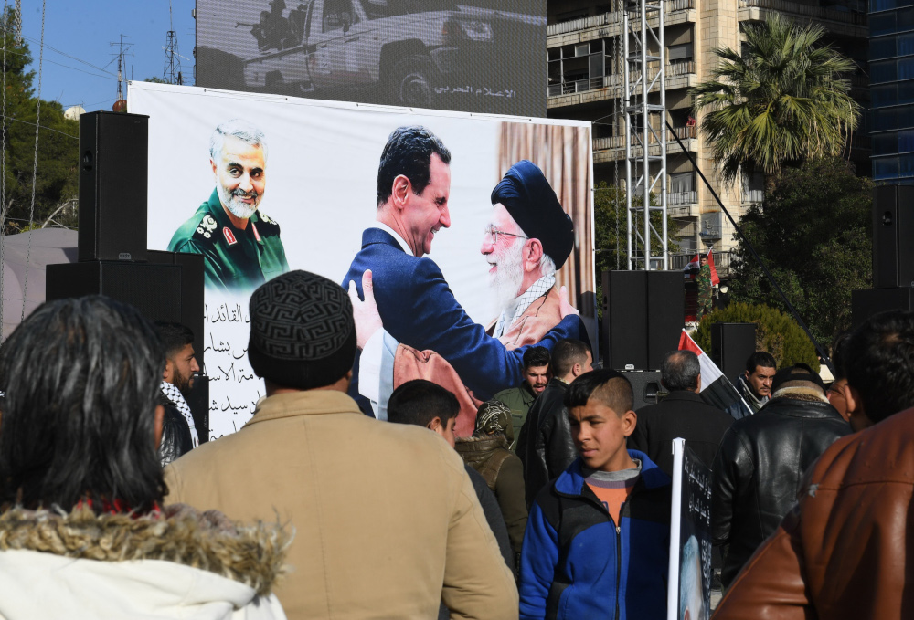 Syrian demonstrators look at a poster bearing the portraits of Iranu00e2u20acu2122s Supreme Leader Ayatollah Ali Khamenei and Syrian President Bashar al-Assad (centre) in the central Saadallah al-Jabiri square in the northern Syrian city of Aleppo January 7, 2020. u00e2u20ac