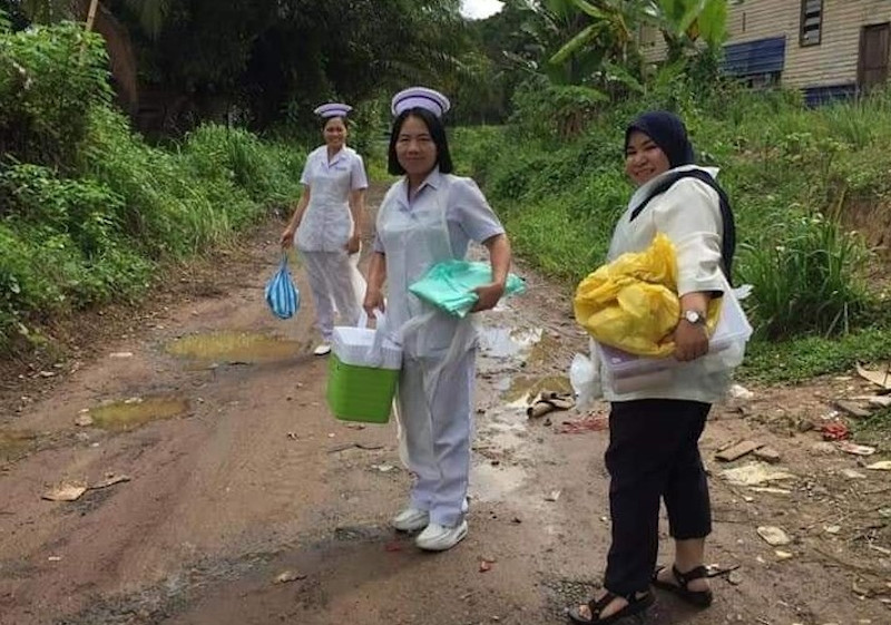 Nurses carrying their medical equipment in a village in Sandakan, Sabah. — Picture courtesy of Facebook/PKPKS