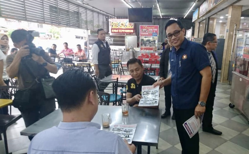 Johor Health, Culture and Heritage Committee chairman Mohd Khuzzan Abu Bakar (far right) providing information to restaurant customers in Bandar Baru Uda in Johor Baru on the smoking ban on food premises January 7, 2020. u00e2u20acu201d Picture by Ben Tan