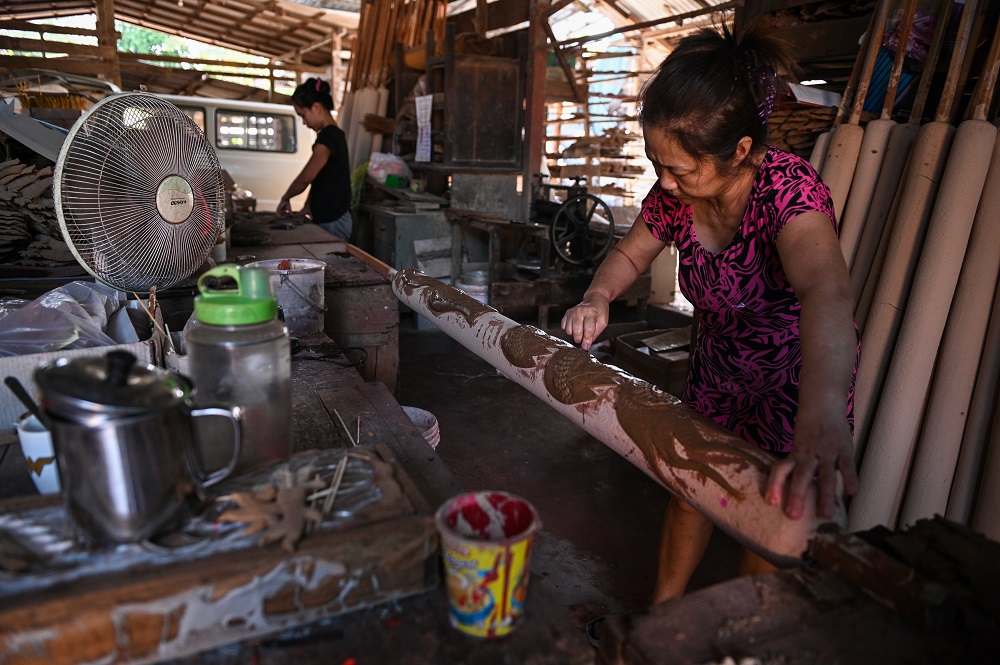This picture taken on January 15, 2020 shows a worker decorating a giant incense sticks at a factory ahead of the Lunar New Year celebrations in Kubang Semang, Penang. — AFP pic