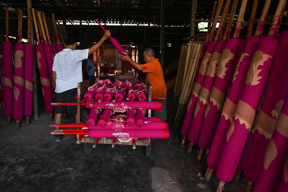 This picture taken on January 15, 2020 shows workers loading giant incense sticks on a cart at a factory ahead of the Lunar New Year celebrations in Kubang Semang, Penang. — AFP pic