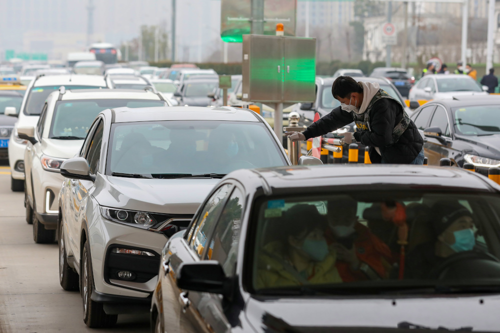 A staff member from a local sanitation and epidemic prevention team checks body temperature of a passenger in a car at a toll station in Wuhan, Hubei province January 23, 2020. u00e2u20acu201d Picture by China Daily via Reuters