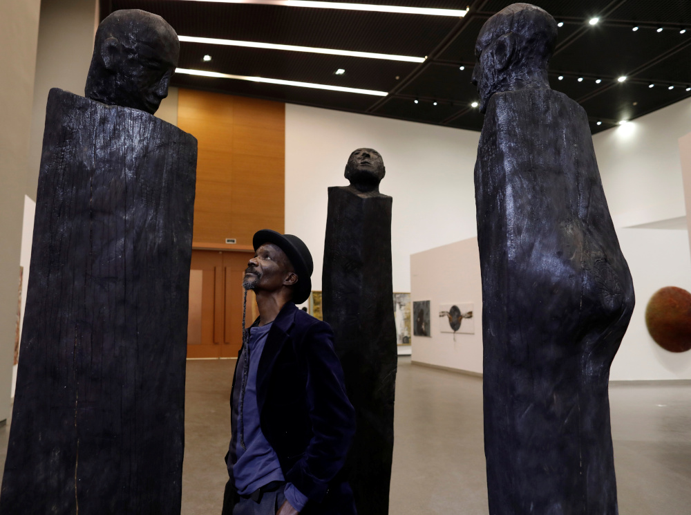 Ivory Coastu00e2u20acu2122s artist Jems Koko Bi poses beside his cedar sculpture exhibited at u00e2u20acu02dcLend Me Your Dreamu00e2u20acu2122, an itinerant exhibition of 33 African artists currently displayed at the Museum of Black Civilisations in Dakar, Senegal January 13, 2020. u00e2u20acu201d Reut