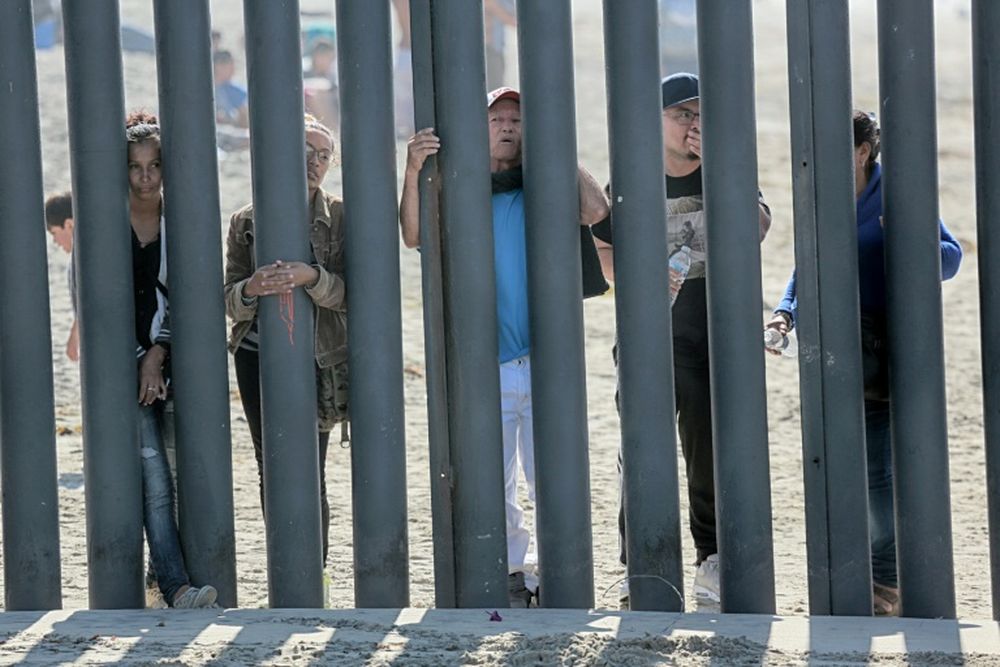File picture shows Honduran caravan members looking through through a fence at the US-Mexico border in San Ysidro, California in November 2018. u00e2u20acu201d AFP pic