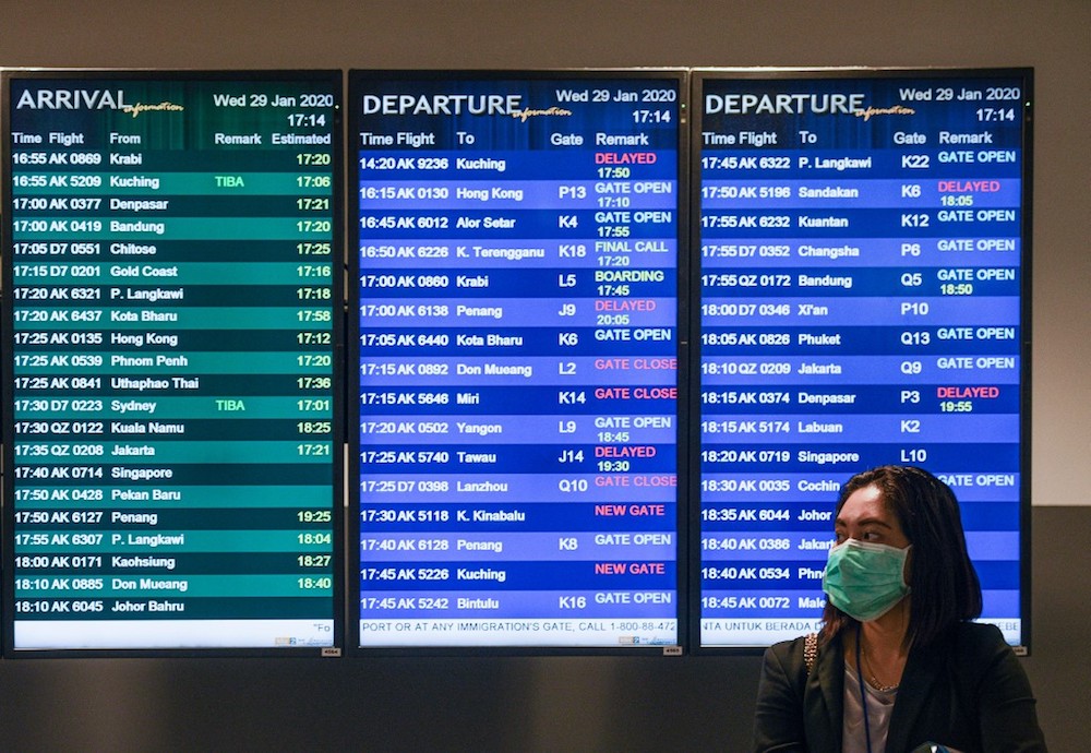 A woman wearing face mask stands in front of the flight information screen at KLIA2 in Sepang January 29, 2020. u00e2u20acu201d AFP pic