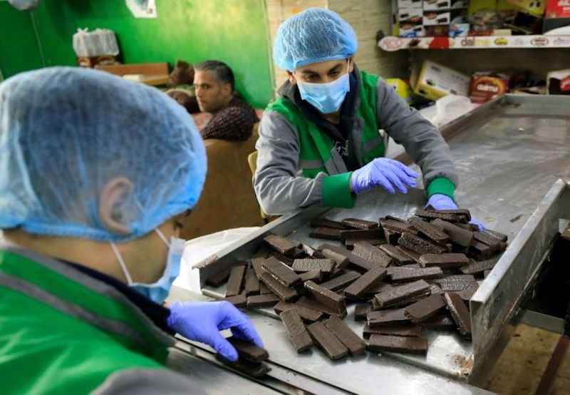 Workers at al-Arees sweets factory in Gaza City sort a batch of chocolate-covered biscuits. u00e2u20acu201d AFP pic