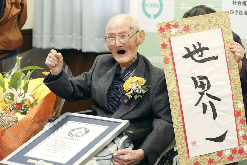 112-year-old Chitetsu Watanabe poses next to the calligraphy reading 'World's Number One' after being awarded as the world's oldest living male by Guinness World Records, February 12, 2020, in this photo released by Kyodo. u00e2u20acu201dKyodo handout via Reuters