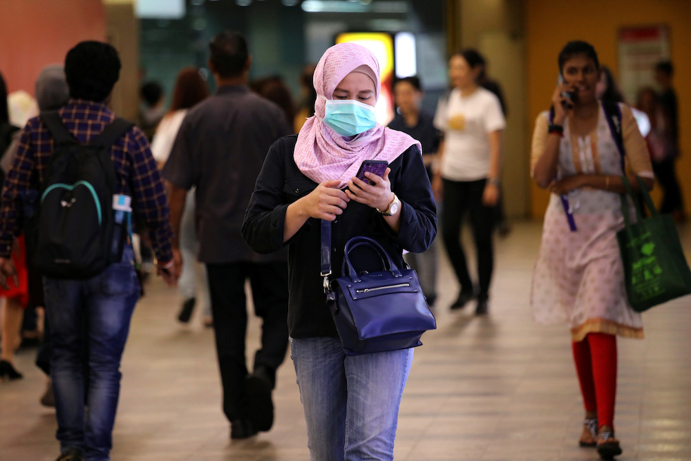 A passenger wearing a protective face mask uses her phone at a Light Rail Transit station in Kuala Lumpur January 31, 2020. u00e2u20acu201d Reuters pic