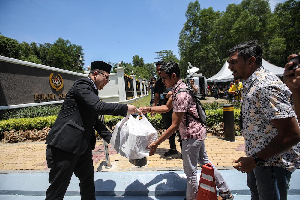 A palace representative distributes food and drinks to media personnel camped ouside Istana Negara, February 29, 2020. u00e2u20acu201d Picture by Hari Anggara