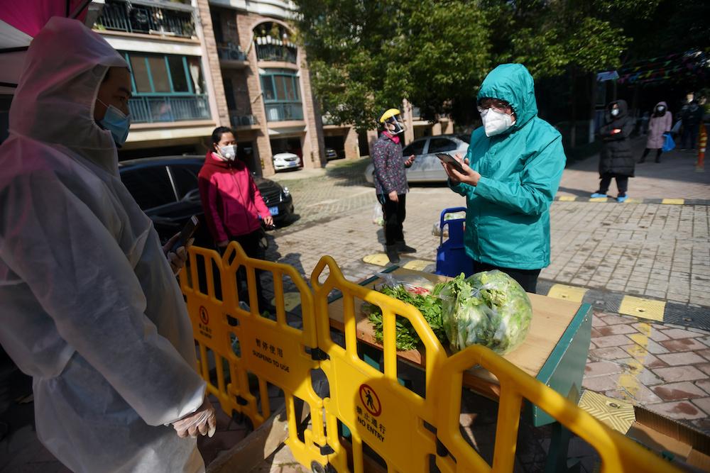 A resident uses a mobile phone to pay for vegetables purchased through group orders at a collection point set up at the entrance of a residential compound in Wuhan, the epicentre of the novel coronavirus outbreak, Hubei province, China February 21, 2020. 