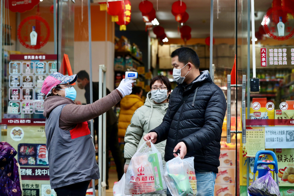 A worker measures body temperature of people leaving a supermarket in Qingshan district following an outbreak of the novel coronavirus in Wuhan, Hubei province, China February 7, 2020. u00e2u20acu201d Reuters pic nnn