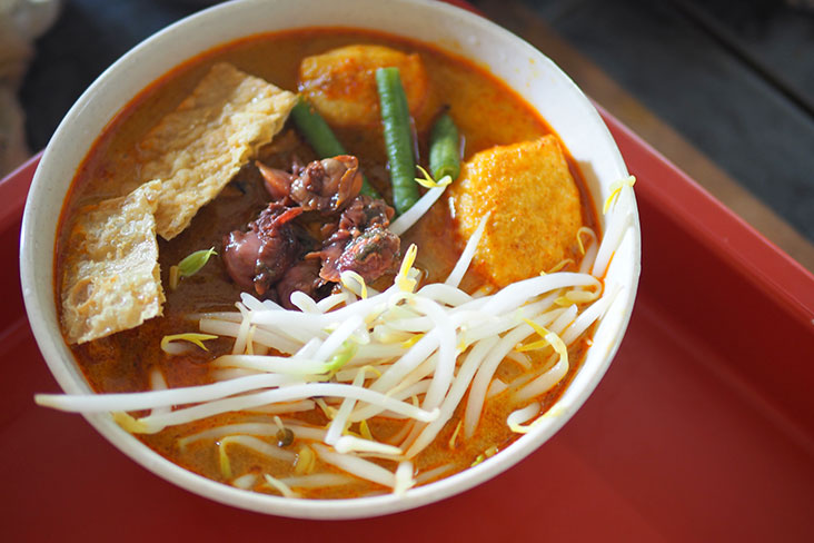 A bowl of curry mee is served with beancurd puffs, long beans, bean sprouts and fried ’fuchuk’