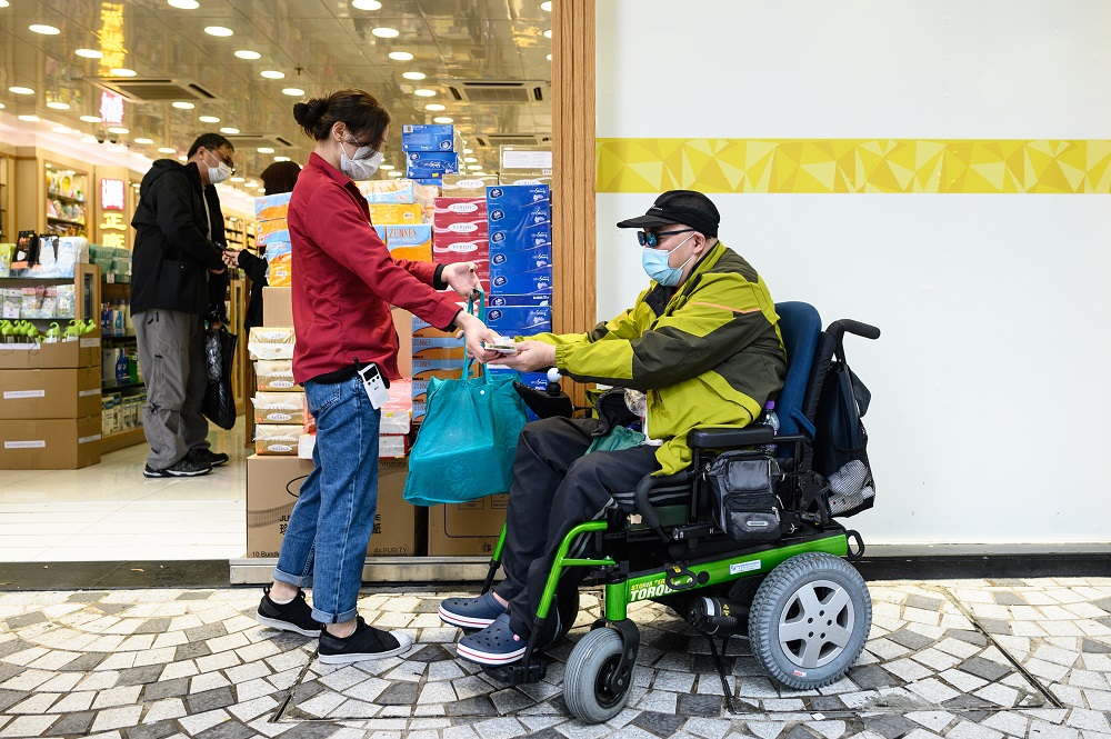 This photo taken on February 13, 2020 shows muscular atrophy patient Steven Yan (right) buying a bag of paper towels from a pharmacy in the Sheung Shui district of Hong Kong. u00e2u20acu201d AFP pic