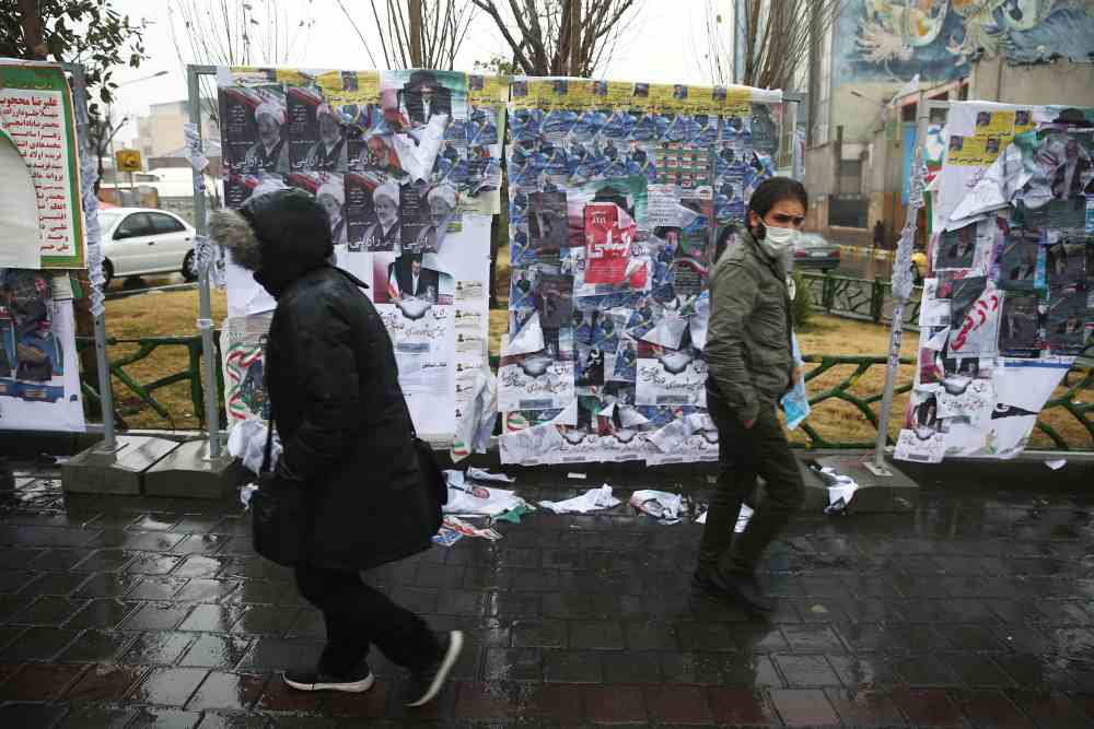 People walk past parliamentary election campaign posters at the end of the parliamentary election day in Tehran February 20, 2020. u00e2u20acu2022 WANA (West Asia News Agency)/Nazanin Tabatabaee pic via Reuters