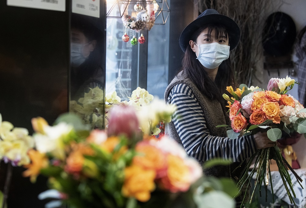 This photo taken on February 12, 2020 shows florist Zhao Yuanyuan wearing a protective face mask as she arranges flowers in her shop in Shanghai ahead of Valentine's Day. u00e2u20acu201d AFP pic 