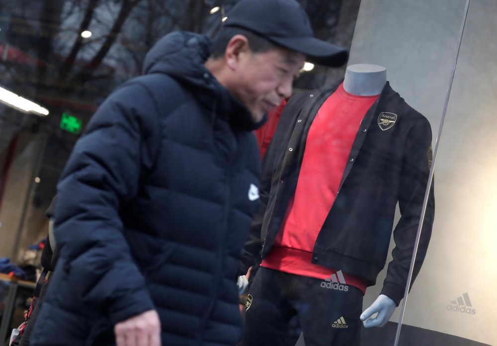 A man walks past an Adidas shop window where a model is dressed in sport outfit with English soccer club Arsenalu00e2u20acu2122s logo, in Beijing, December 16, 2019. u00e2u20acu201d Reuters pic