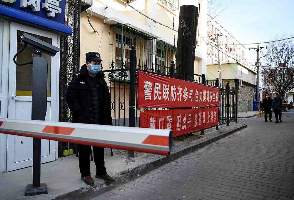 A security guard wearing a protective face mask at a compound with a banner reminding people to wear masks and wash hands in Beijing February 1, 2020. u00e2u20acu201d AFP pic