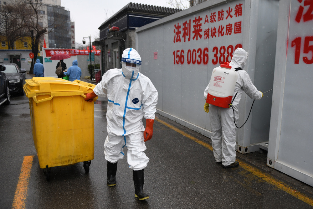 A worker carts a bin loaded with medical waste as another disinfects between containers at the Youan Hospital in Beijing February 14, 2020. Youan Hospital is one of 20 hospitals in Beijing treating Covid-19 patients. u00e2u20acu201d AFP pic   