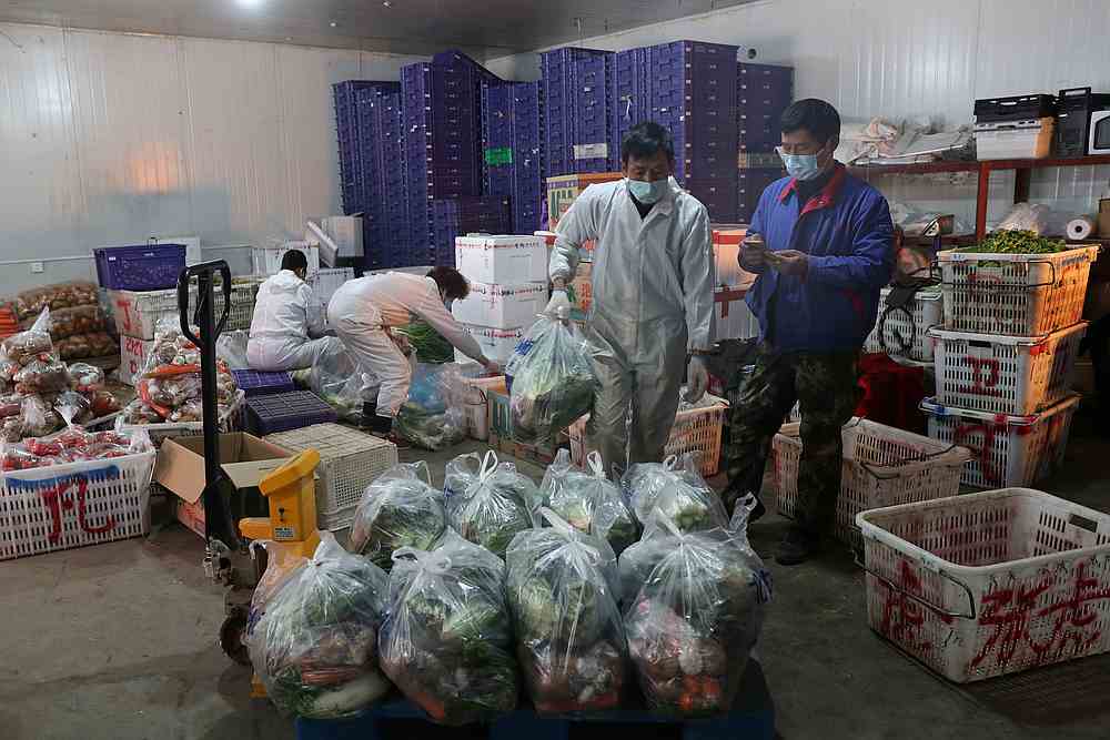 Workers wearing face masks pack vegetables at Baishazhou market in Wuhan, the epicentre of the novel coronavirus outbreak, in Hubei province, China February 19, 2020. u00e2u20acu201d China Daily pic via Reuters