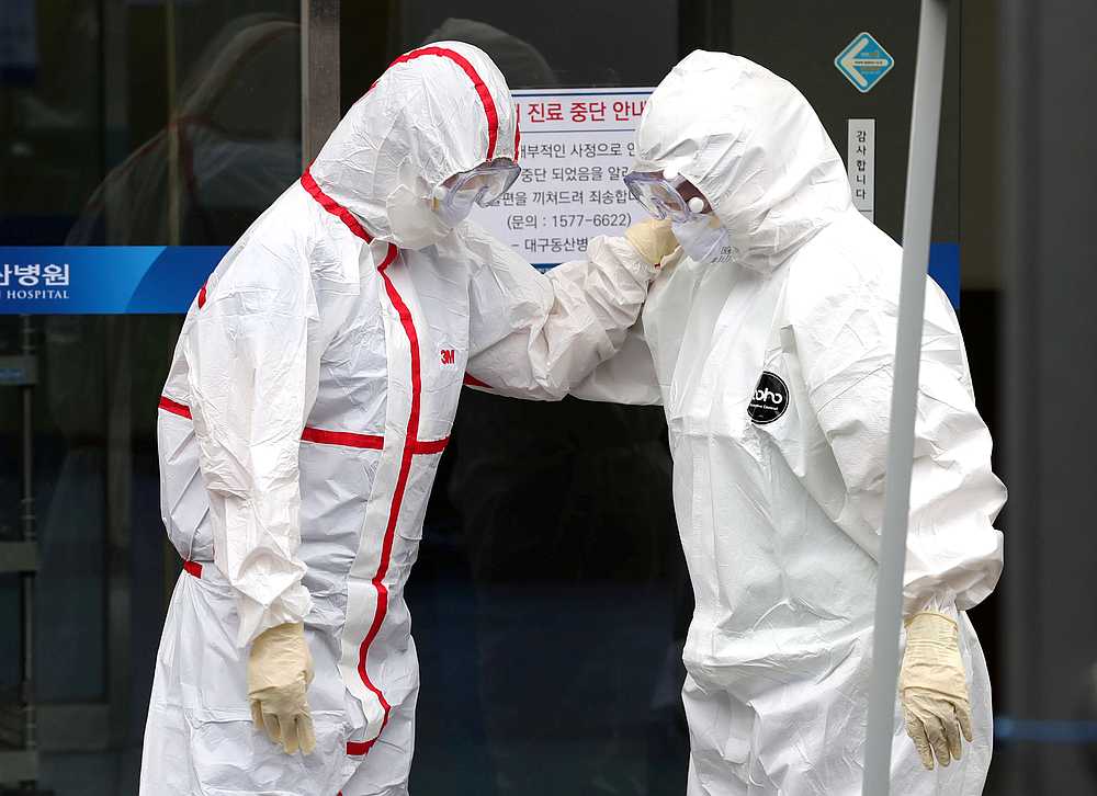 Medical workers wearing protective gear outside a hospital in Daegu, South Korea February 28, 2020. u00e2u20acu201d Yonhap pic via Reuters