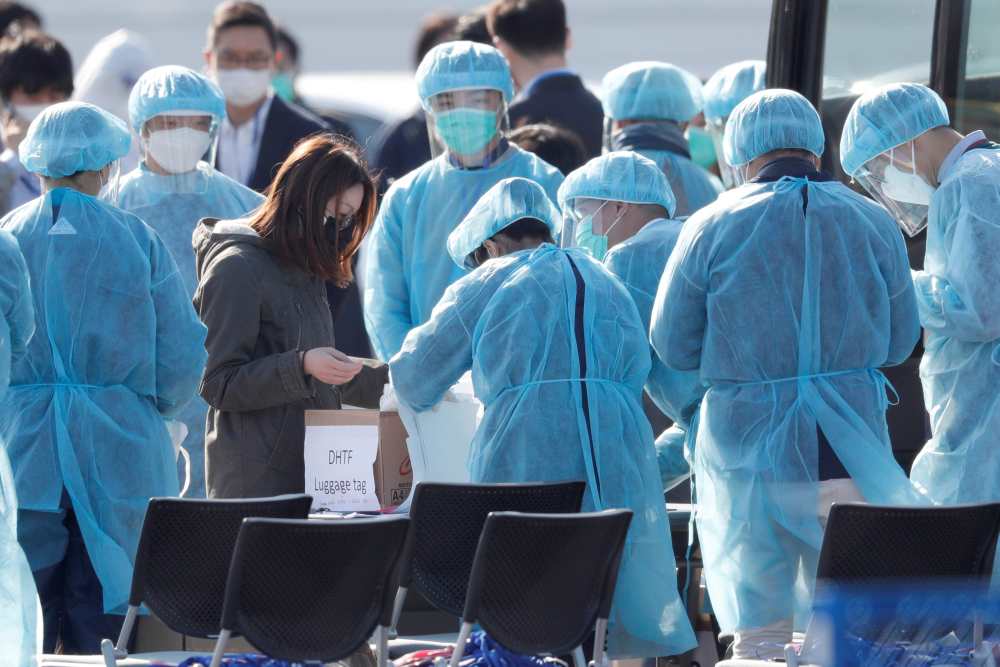 Workers in protective gear assist a passenger in a face mask after she leaves the coronavirus-hit cruise ship Diamond Princess at Daikoku Pier Cruise Terminal in Yokohama, south of Tokyo February 21, 2020. u00e2u20acu2022 Reuters pic