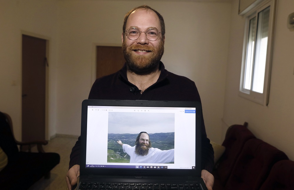 Israeli Avi Tfilinksi, a former ultra-orthodox Jew from Jerusalem, poses while showing an old religious picture of him, at his apartment in Abu Ghosh on the outskirts of the holy city on February 10, 2020. u00e2u20acu2022 AFP pic