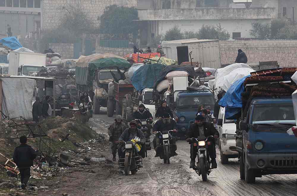 Men riding on motorbikes pass the trucks that carry belongings of displaced Syrians, in northern Idlib, Syria January 30, 2020. u00e2u20acu201d Reuters pic