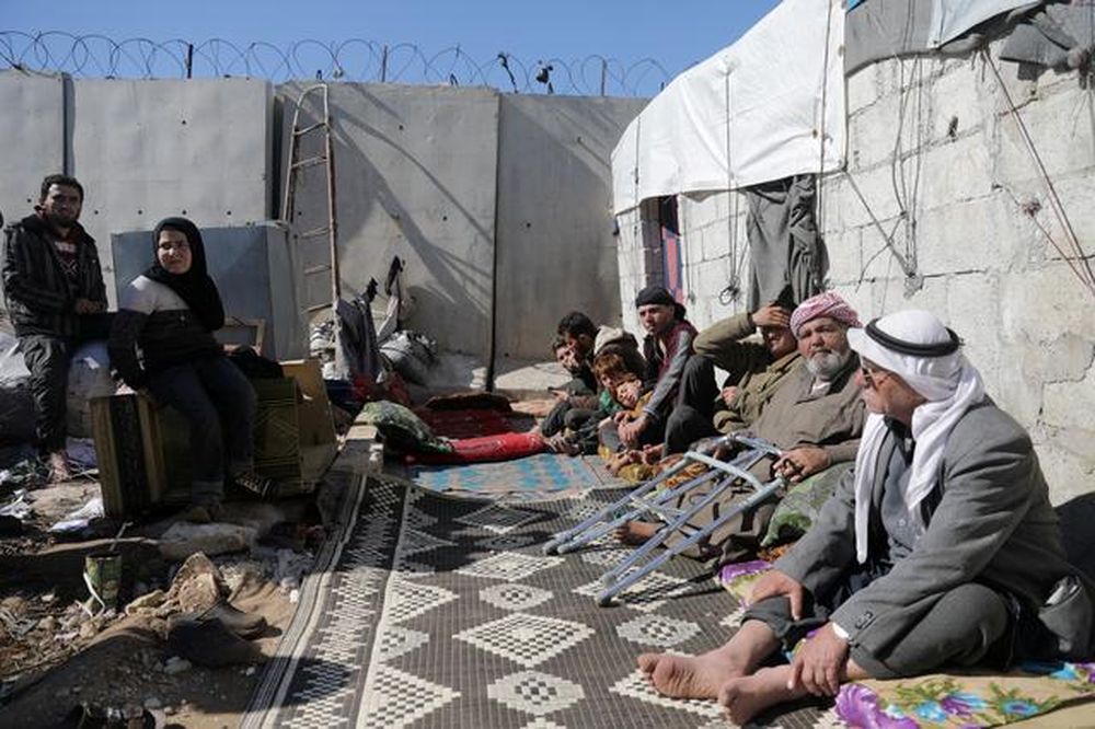 An internally displaced Syrian family sit together outside a tent near the wall in Atmah IDP camp, located near the border with Turkey, Syria February 26, 2020. u00e2u20acu201d Reuters pic