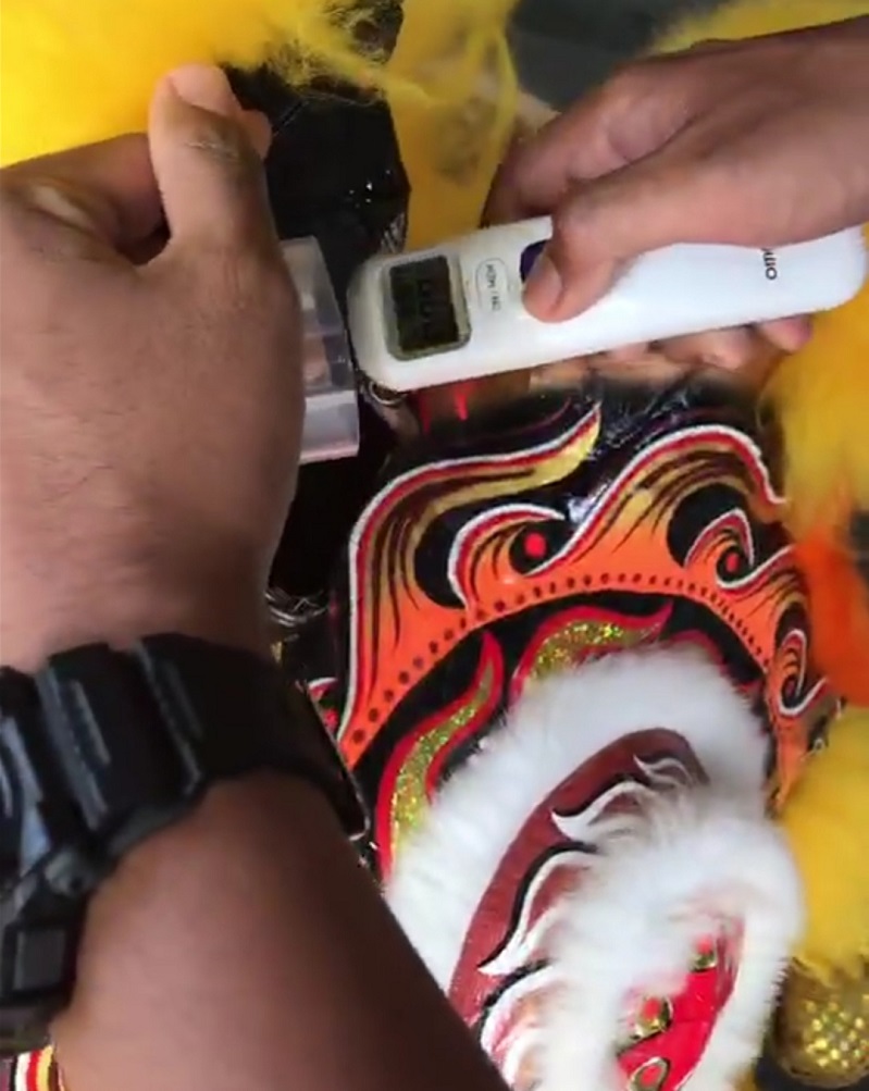 The auxiliary policeman checking on the lion heads for fever with an infrared body thermometer. u00e2u20acu201d Picture from Facebook