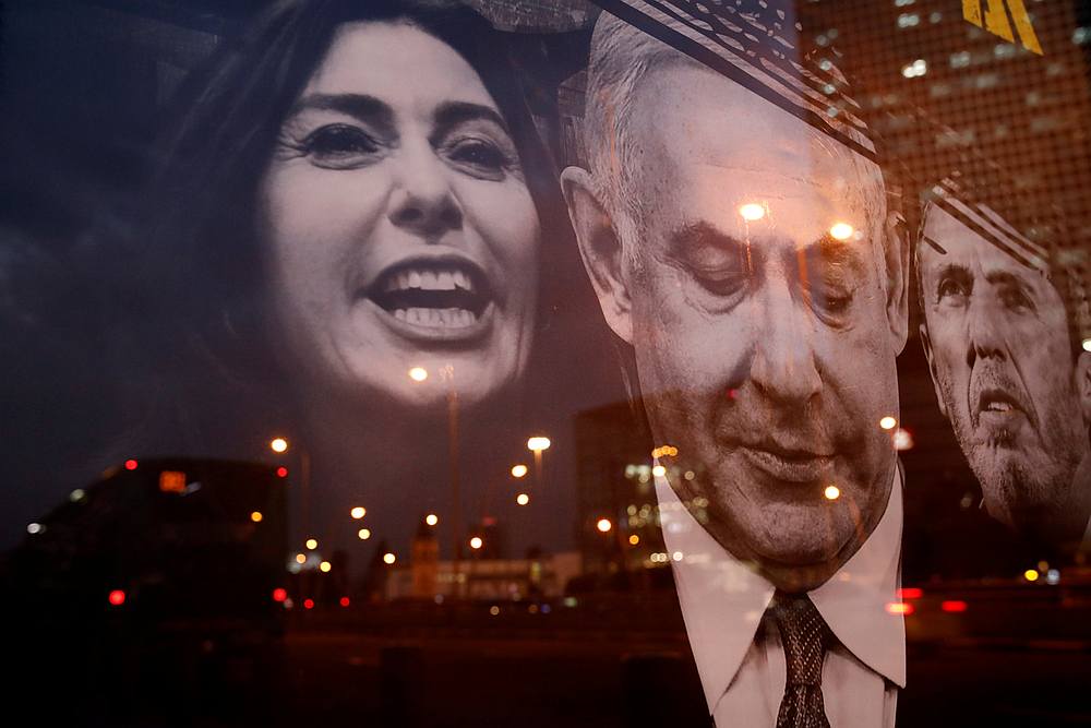 City lights are reflected on a campaign poster depicting Israeli Prime Minister Benjamin Netanyahu, Minister of Culture and Sport Miri Regev and Education Minister Rafi Peretz in Tel Aviv February 23, 2020. u00e2u20acu201d Reuters pic