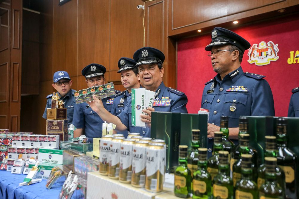 Perak Customs director Mohamad Sarpin poses with seized contraband cigarettes and alcohol worth over RM2 million during a press conference in Ipoh February 25, 2020. u00e2u20acu201d Picture by Farhan Najibnn