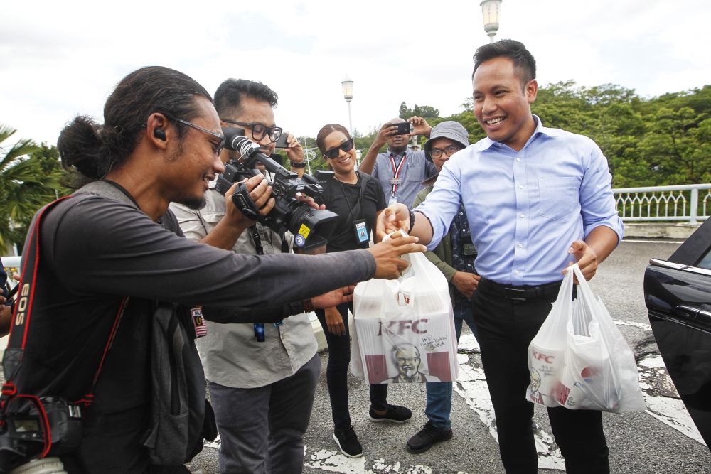 Staff from the Prime Ministeru00e2u20acu2122s Office distributes food from KFC to members of the media outside Perdana Putra February 25, 2020. u00e2u20acu2022 Picture by Shafwan Zaidon