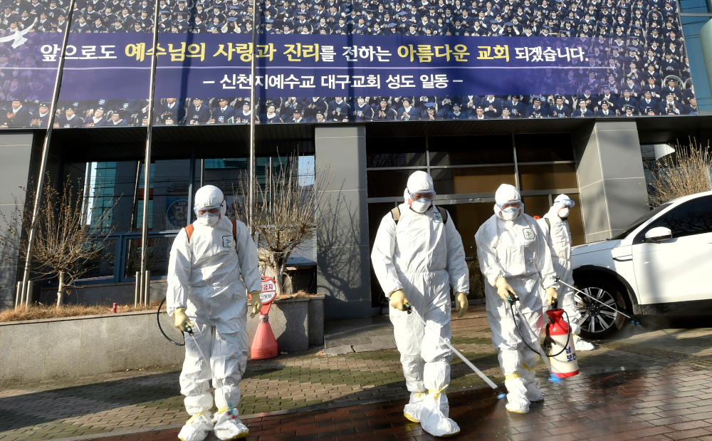 This handout picture taken February 19, 2020 shows South Korean health officials wearing protective suits and spraying disinfectant in front of the Daegu branch of the Shincheonji Church of Jesus in the Daegu. u00e2u20acu201d Daegu Metropolitan City Namgu handout pic