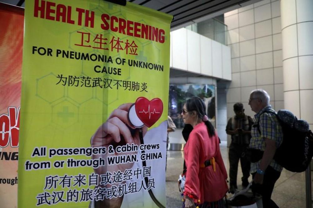Passengers pass a banner about the Wuhan Pneumonia at a thermal screening point in the international arrival terminal of Kuala Lumpur International Airport in Sepang, January 21, 2020. u00e2u20acu201d Reuters pic