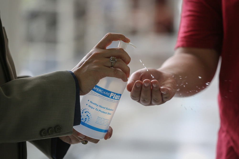 Staff member from mosque distributes hand sanitiser to worshippers during Friday prayers at Sultan Salahuddin Abdul Aziz Shah Mosque in Shah Alam March 13, 2020. u00e2u20acu201d Picture by Yusof Mat Isa