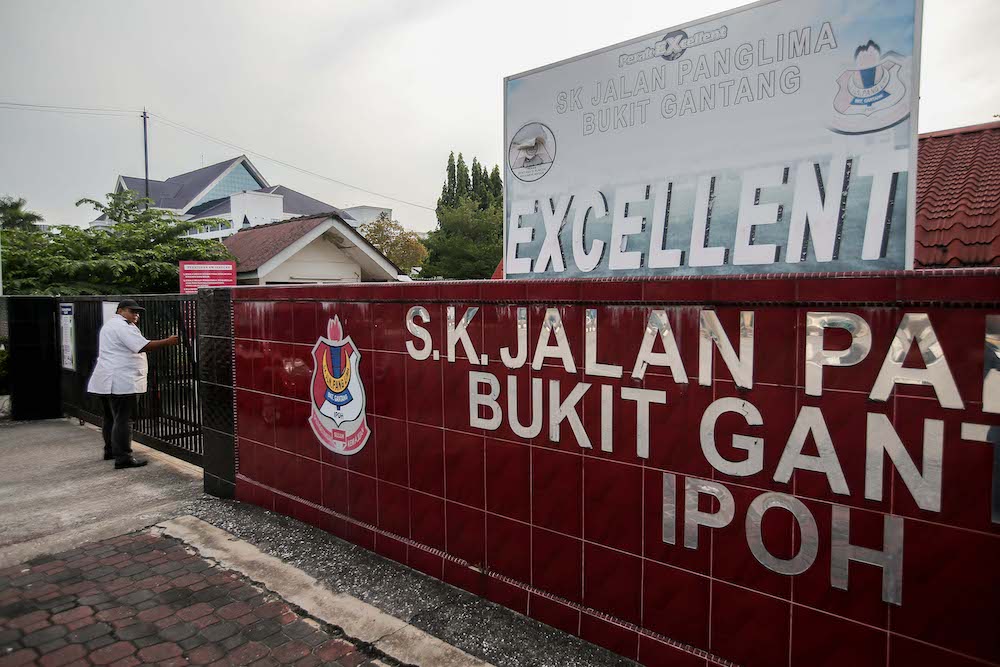 A security guard from SK Panglima Bukit Gantang Ipoh closes the school gate under a nationwide Movement Control Order from March 18 until March 31 due to the Covid-19 outbreak, March 17, 2020. u00e2u20acu201d Picture by Farhan Najib