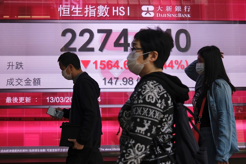 People wear protective masks as they walk past a panel displaying the Hang Seng Index during morning trading, following the outbreak of the new coronavirus, in Hong Kong March 13, 2020. u00e2u20acu201d Reuters pic