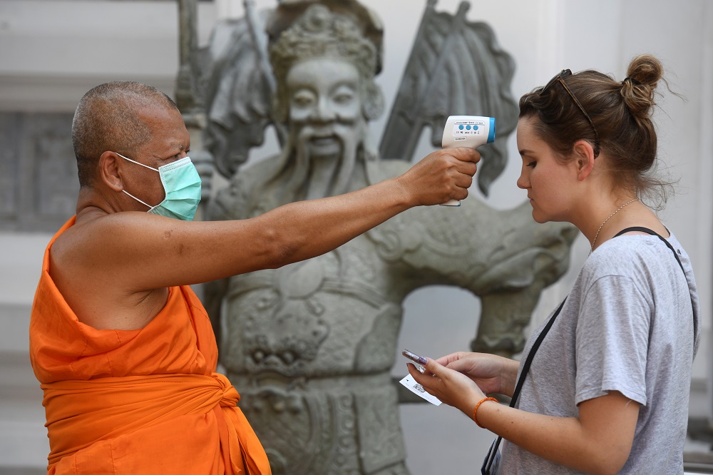 A Buddhist monk check temperture of a visitor at Wat Pho temple as prevention after the coronavirus outbreak in Bangkok March 13, 2020. u00e2u20acu201d Reuters pic
