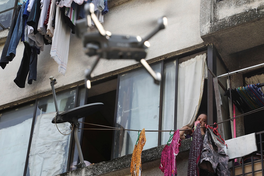 A woman looks at a drone, which is used by Malaysian police to remind citizens to stay at home during the movement control order due to the outbreak of the coronavirus disease, in Kuala Lumpur March 24, 2020. — Reuters pic