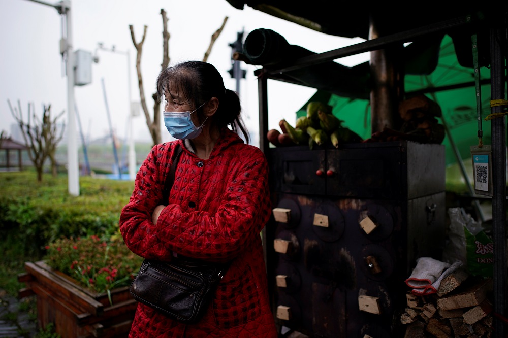 Li Yu, 55, a peddler selling corn, wears a face mask at an ancient city wall in Jingzhou, after the tourist attraction reopened as the lockdown was eased in Hubei province, the epicentre of China's coronavirus disease outbreak, March 26, 2020. u00e2u20acu201d Reuters