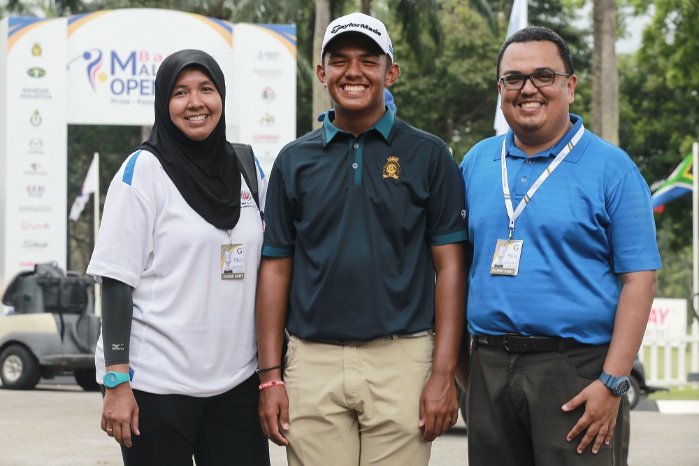 Hariz posing for a picture with his parents.